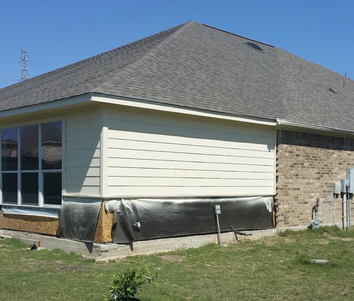 Room addition corner with house wrap installed, tying into the existing brick