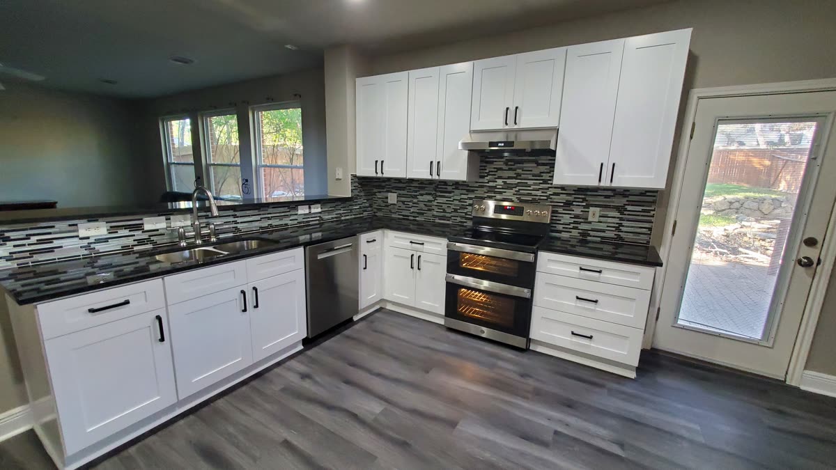 Bright white shaker kitchen with a stainless double-oven range and tile backsplash