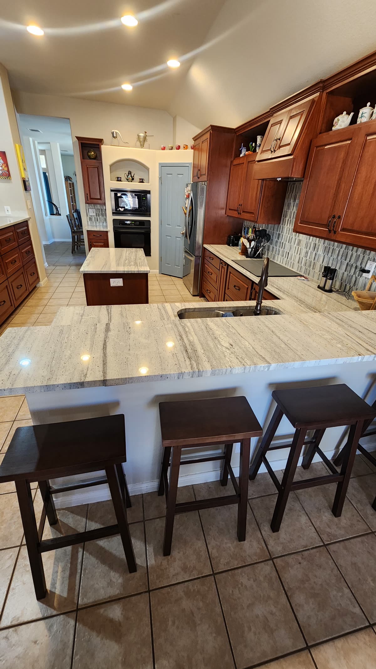 White kitchen with mosaic tile backsplash and stainless refrigerator